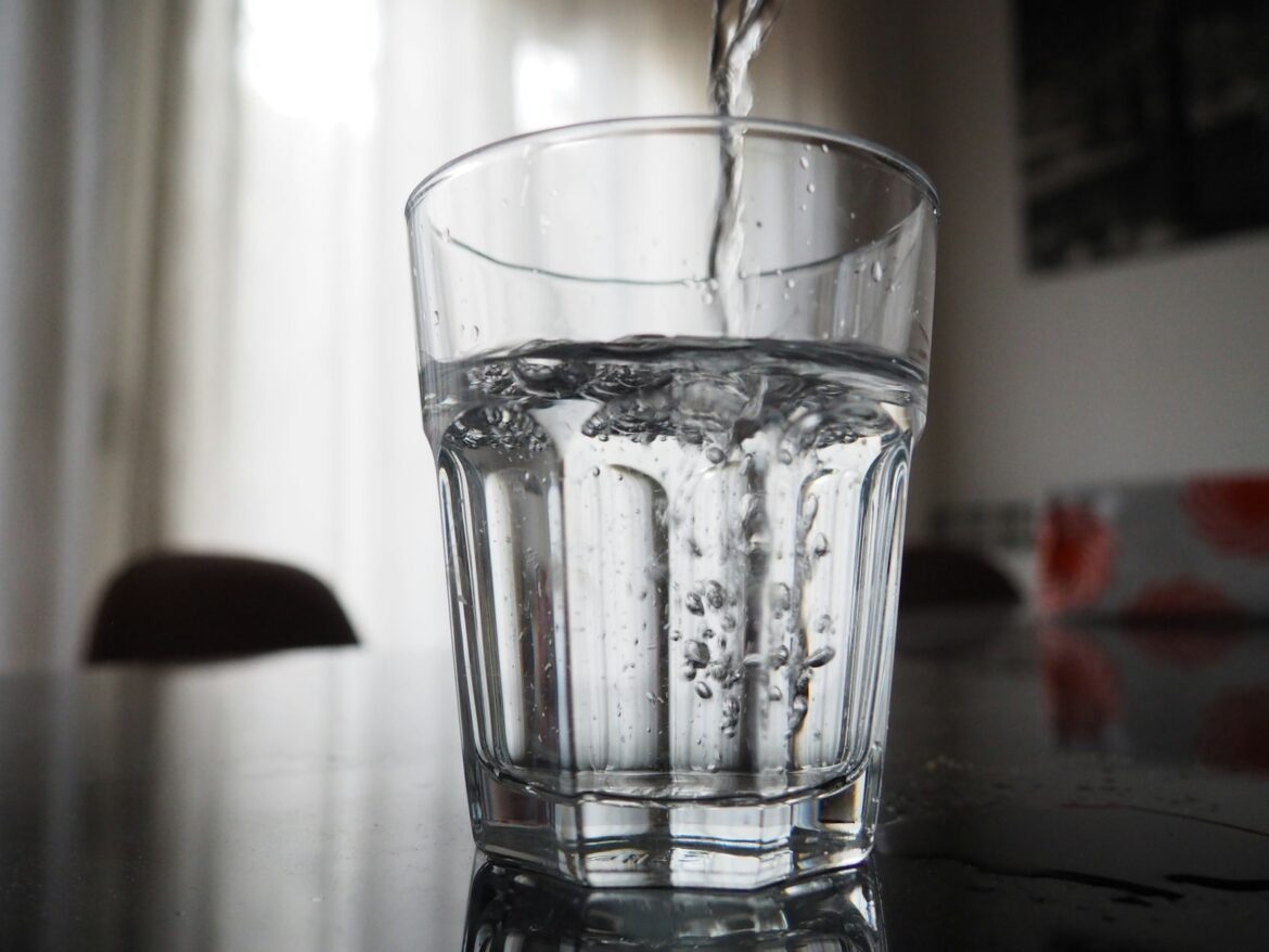 Glas water wordt gevuld bij de kraan
