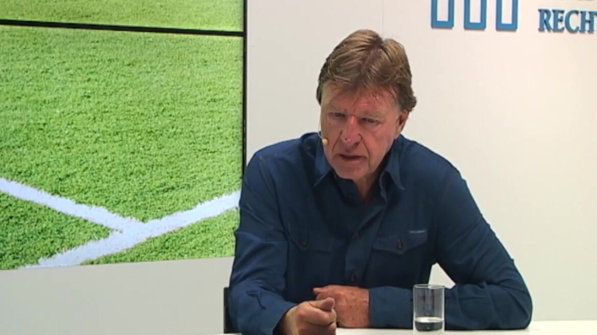 Aad de Mos aan tafel in een tv-studio tijdens een interview